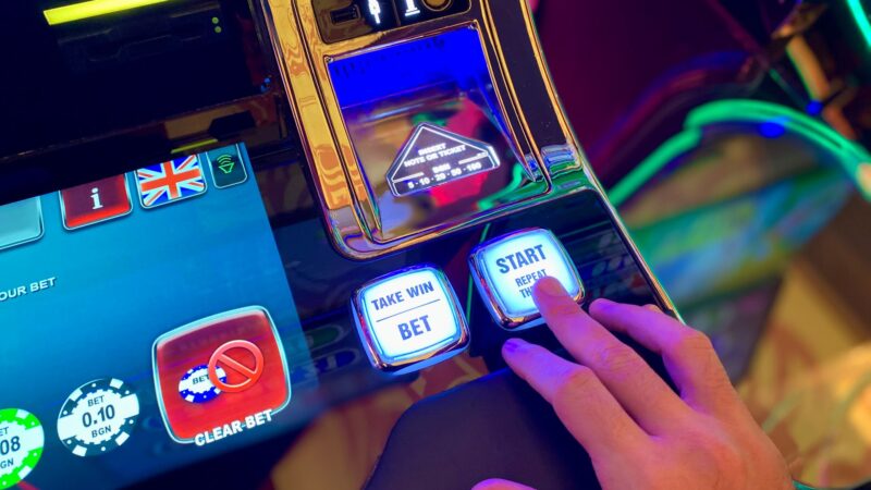 Ruka na osvetljenim dugmadima slot automata – Hold and Win mehanika u slot igrama