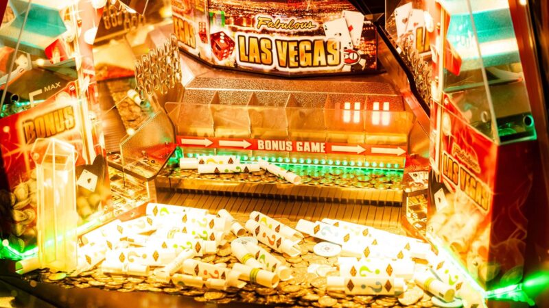osvetljen slot displej sa neonskim svetlima, novčići i karte za poker u kadru, Las Vegas atmosfera — horizontalna, živopisna
